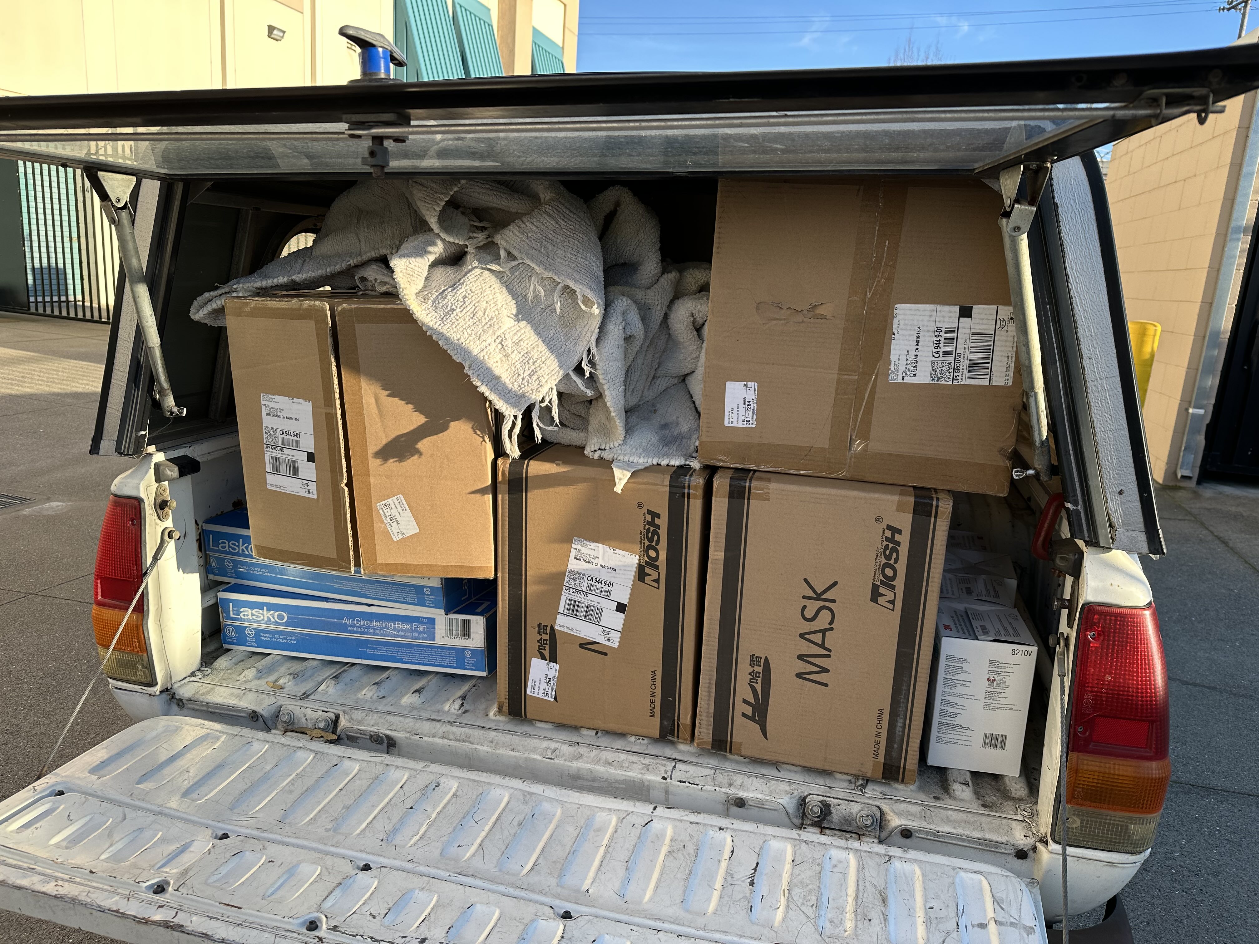 back of an old pickup loaded with masks and other supplies